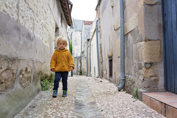 Obraz na płótnie Canvas Child, boy walking in a beautiful small village street in France