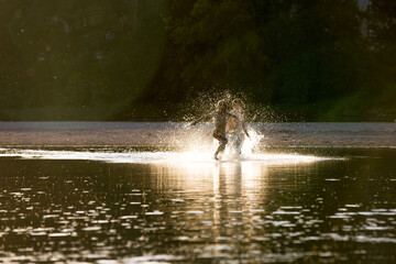 Beautiful portrait of children in lake, kids playing in the water on sunset, summer