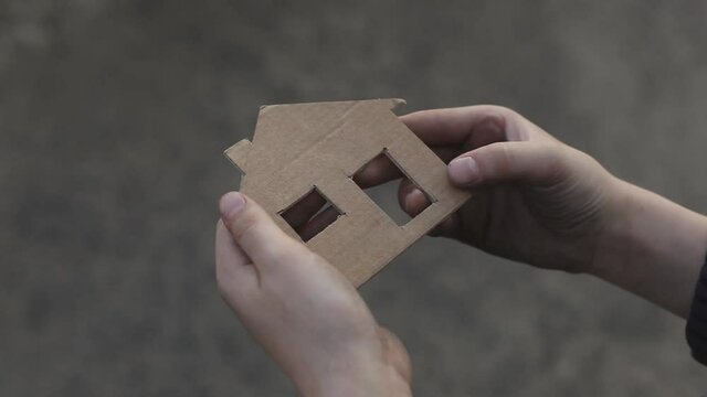 homeless boy holding a cardboard house, dirty hand