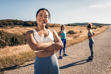 Portrait of young woman preparing for running with her friends outdoors.
