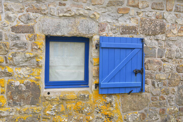 La petite fenêtre et le volet bleu sur le vieux mur en pierres, région Bretagne, France