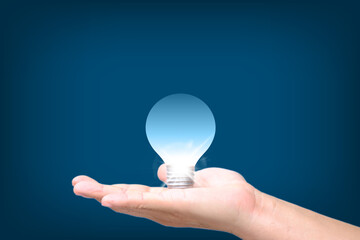 Hand holding Glowing light bulb in idea, innovation and inspiration concept, illuminated light bulb on blue bakground