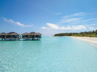 View of water villas (bungalows) near the island in the Maldives, surrounded by the beautiful transparent turquoise Indian Ocean. The concept of an exotic summer vacation, resort.