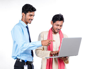 Fototapeta premium Indian bank officer or corporate government employee showing some information to farmer in laptop.