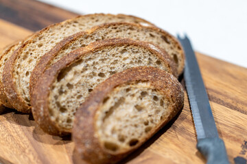 Fresh sliced bread on wooden board with knife in kitchen