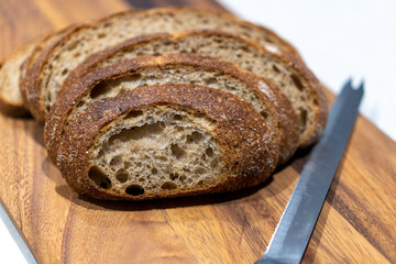 Fresh sliced bread on wooden board with knife in kitchen