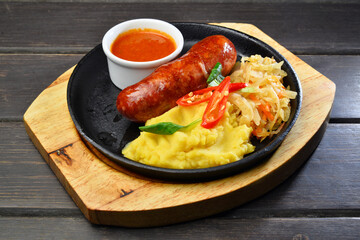Grilled sausage with mashed potatoes and sauce on dark wooden table