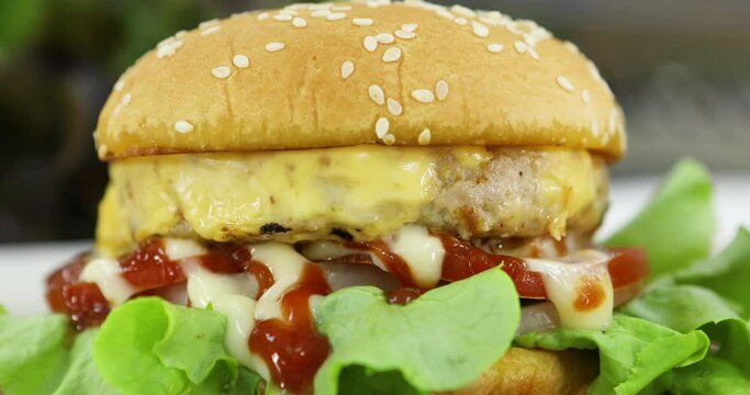Piece of hamburgers with sesame topping on bread on wooden cutting board.