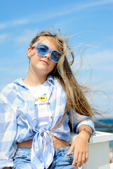 beautiful teenage girl with long hair wearing blue glasses and a plaid shirt portrait