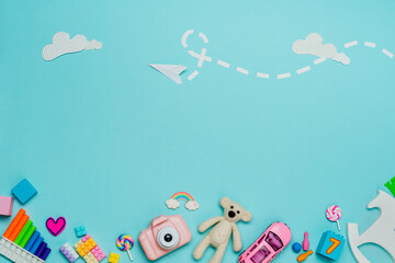 Variety of plastic and wooden kids toys on blue background with paper plane