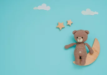 Fototapeten Kids toy knitted soft bear with wooden moon and stars on blue background © lithiumphoto