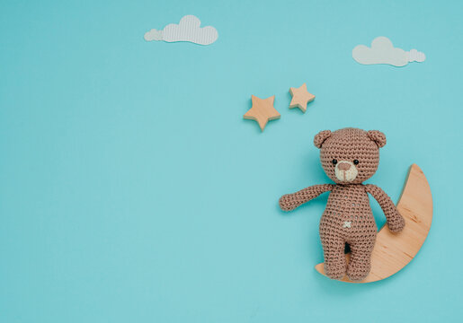 Kids toy knitted soft bear with wooden moon and stars on blue background