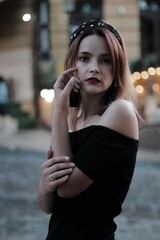 girl in a black short dress on the evening street. against the backdrop of lights, shops.