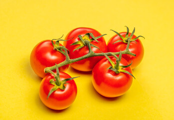 red tomatoes with a green stalk, on a yellow background, concept,