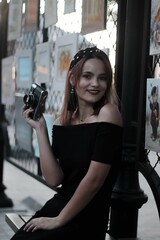 girl in a black short dress on the evening street. against the backdrop of lights, shops.