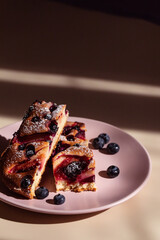 Open fruit pie with plums, blueberries and black currants in a beam of light and with contrasting shadows