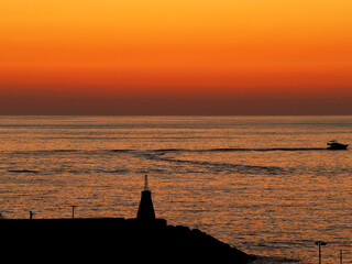 Beautiful after sunset sky colors with a yacht passing by behind a pear in Holiday Beach in Zouk Mosbeh, Lebanon. 