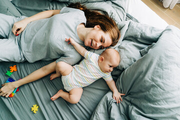 Happy family time together, mom with baby on the bed, top view.