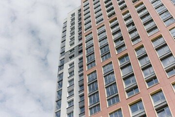 Fototapeta premium The facade of a high-rise residential building on a sunny summer day. a detailed picture of a building in the city. The blue sky is reflected in the windows.