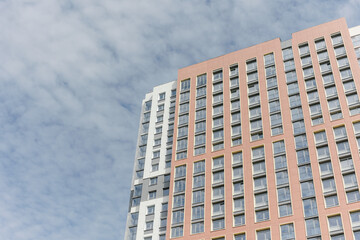 Fototapeta premium The facade of a high-rise residential building on a sunny summer day. a detailed picture of a building in the city. The blue sky is reflected in the windows.