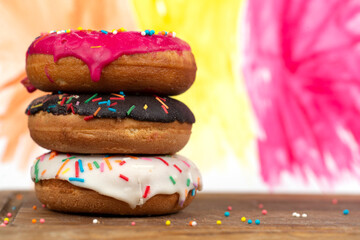 Creative sweet food. A stack of glazed colorful assorted donuts on a bright watercolor painted background.