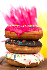 Creative sweet food. A stack of glazed colorful assorted donuts on a bright watercolor painted background.