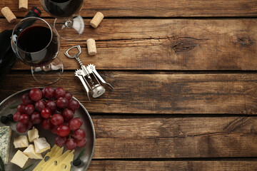 Tasty red wine and snacks on wooden table, flat lay. Space for text