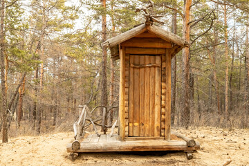 A new wooden toilet log house in a pine forest.
