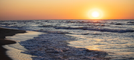 Fototapeta na wymiar Beautiful sunset over the sea. Red sun and waves.