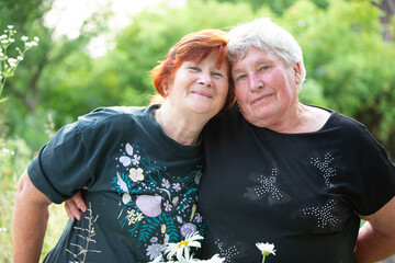 Two older women friends hugging and looking at the camera.