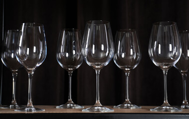 Empty wine glasses on shelf against black background