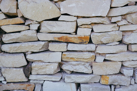 Sandstone Masonry Texture. Retaining Wall Lined With Sandstone Stones. Natural Stone Background. Masonry Wall Made Of Pieces Of Flat Sandstone