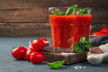 Homemade tomato juice with basil on a wooden background. Side view, close-up.