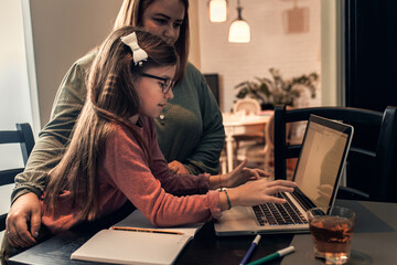 Little girl follow online classes using laptop at home.	