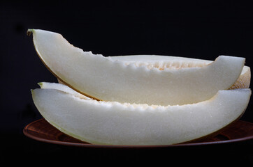 Slices of ripe melon on a clay plate.