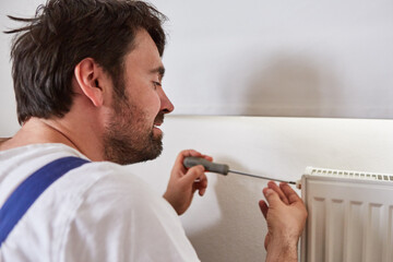 Handyman repairs the radiator of a heater