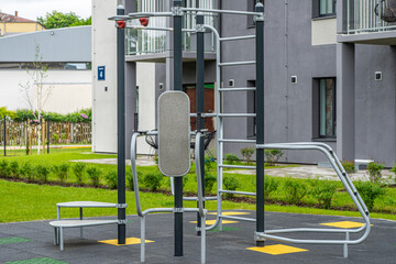 Obraz premium Exercise equipment on playground in yard. Modern residential building.
