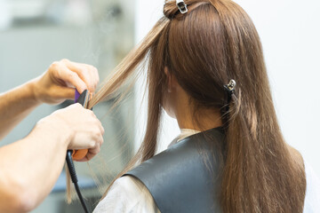 Fototapeta premium ヘアアイロンを使ってセットするスタイリスト