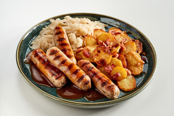 Plate of grilled spicy sausages, cabbage and crispy potatoes