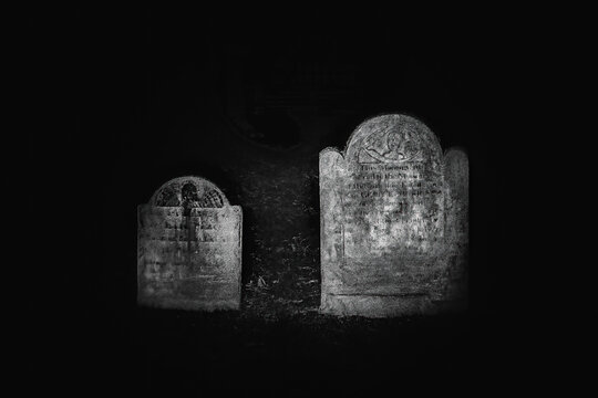 Black and white photo of historical headstones on a night ghost tour in Alexandria, Virginia.