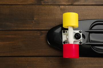 Black skateboard on wooden background, top view. Space for text