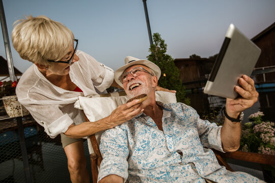 Senior couple enjoying a evening in the cottage near the river, using digital tablet. - Powered by Adobe