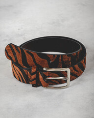 Beautiful black leather belt with brown animal print texture of zebra and silver metal buckle over...