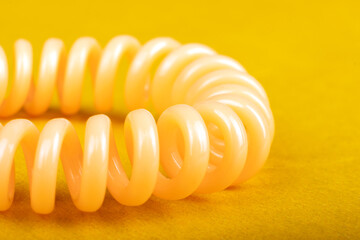 spiral hair tie closeup on yellow background.