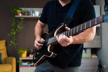 Un hombre toca la guitarra en su casa
