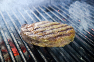 steak cooking over flaming grill