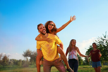 Happy couple covered with colorful powder dyes outdoors. Holi festival celebration