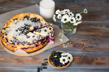 Berry pie. Blueberry casserole on a wooden table. Homemade food. Breakfast with pastries, milk. White flowers. Cheesecake on a wooden background.