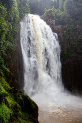 Big waterfall in Thailand with flowing muddy water to the pond.