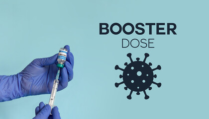Medical worker holding covid syringe and vaccine in front of blue background with booster dose text - obrazy, fototapety, plakaty